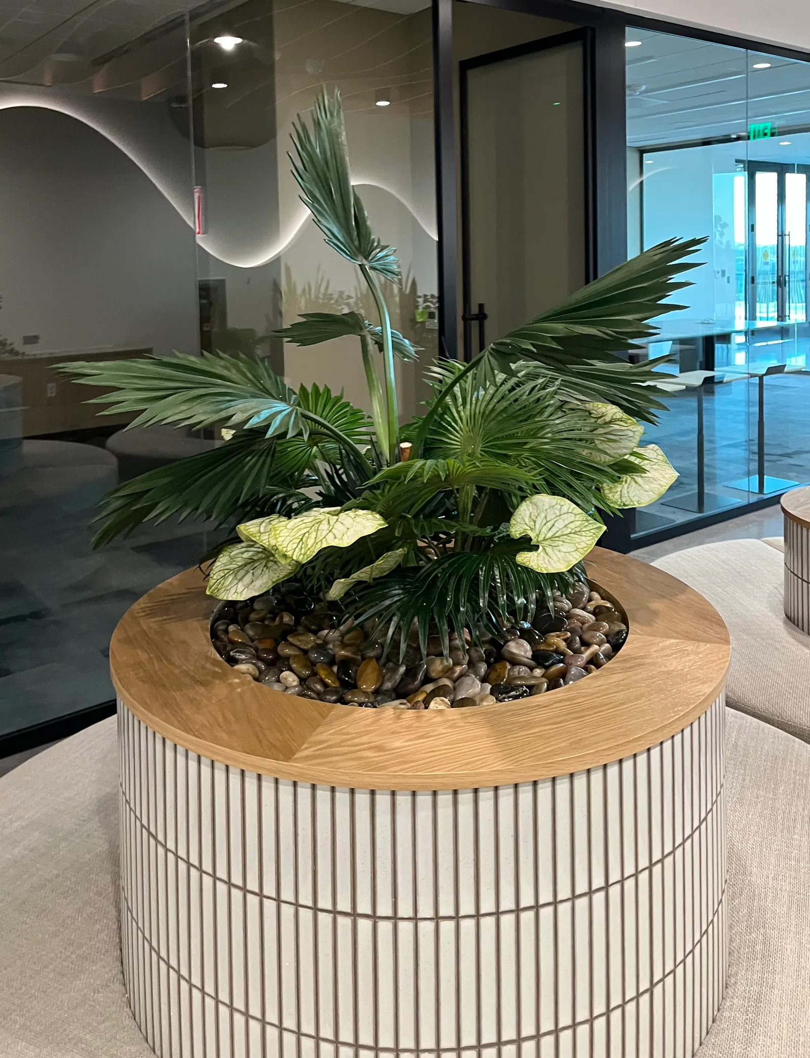A round planter with faux palms and anthuriums