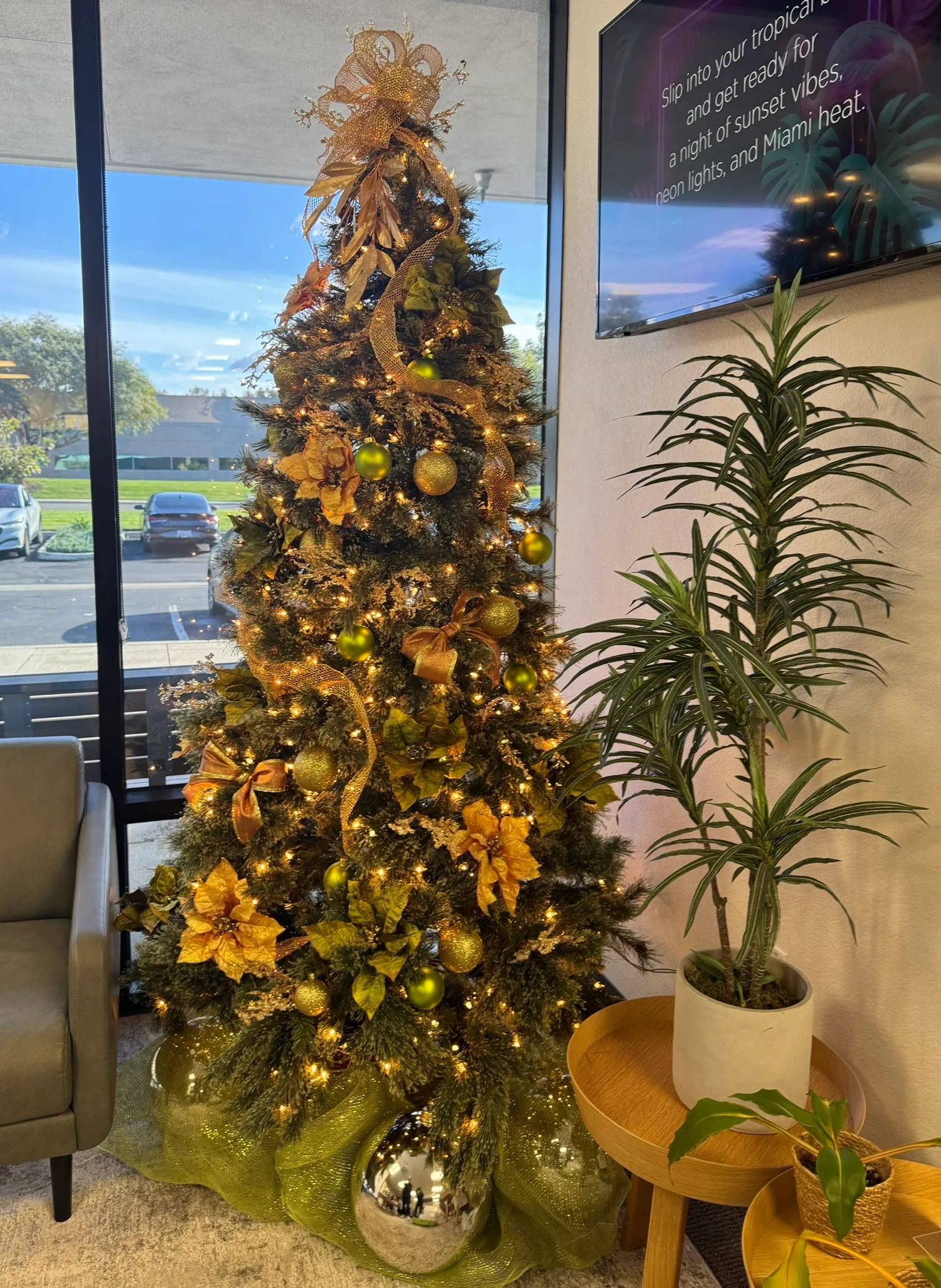 A gold holiday tree beside a window