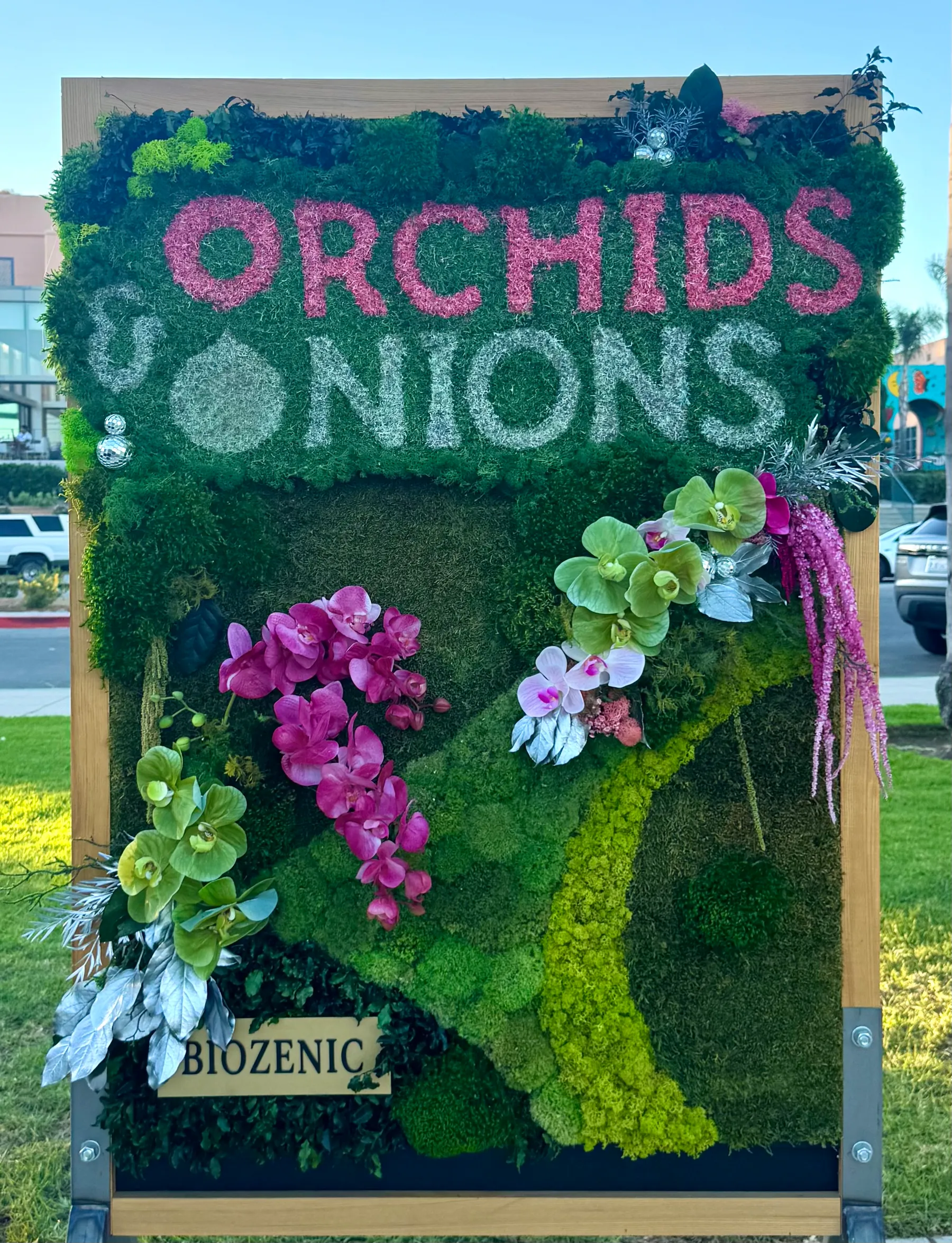 The event name lettered in preserved moss with live orchids