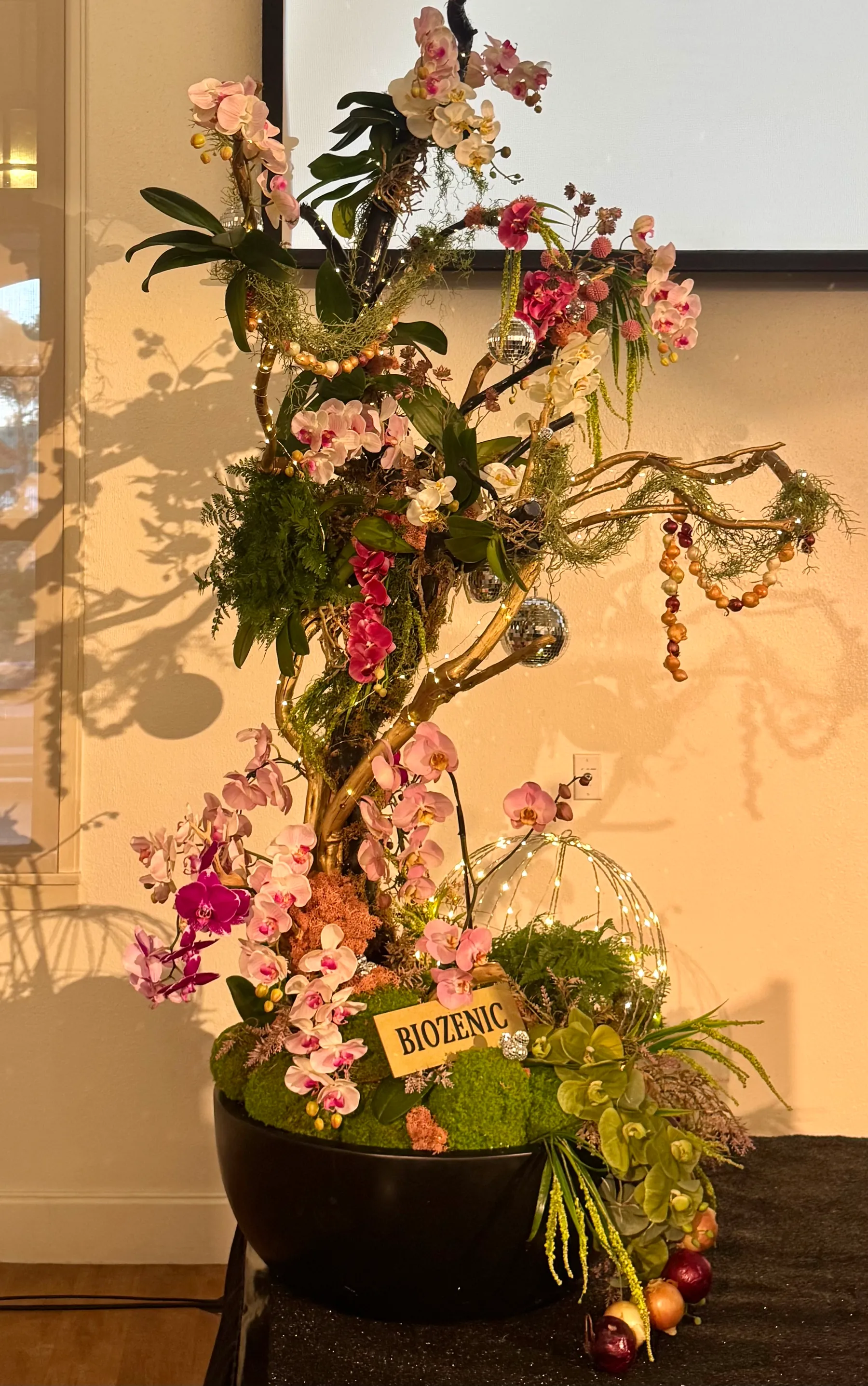 An orchid branch arrangement in a moss bowl at an event